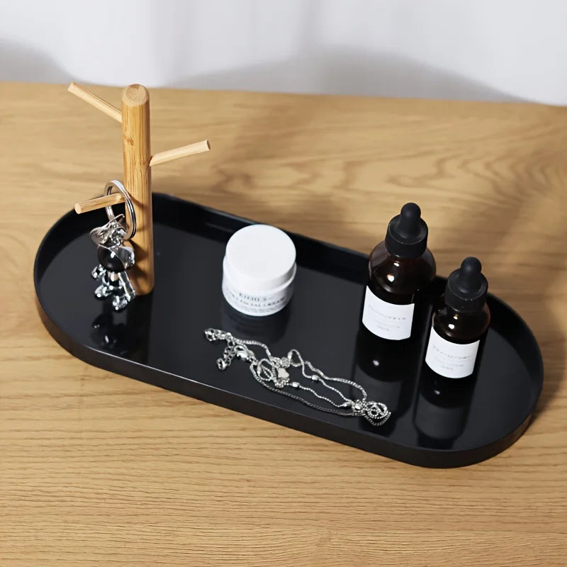 Black key and jewelry tray with wood tree holder, holding keychains, necklace, and skincare bottles on a desk