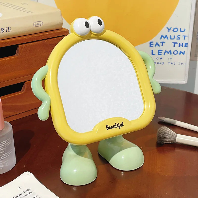 yellow and green cartoon standing mirror on a desk with makeup brushes