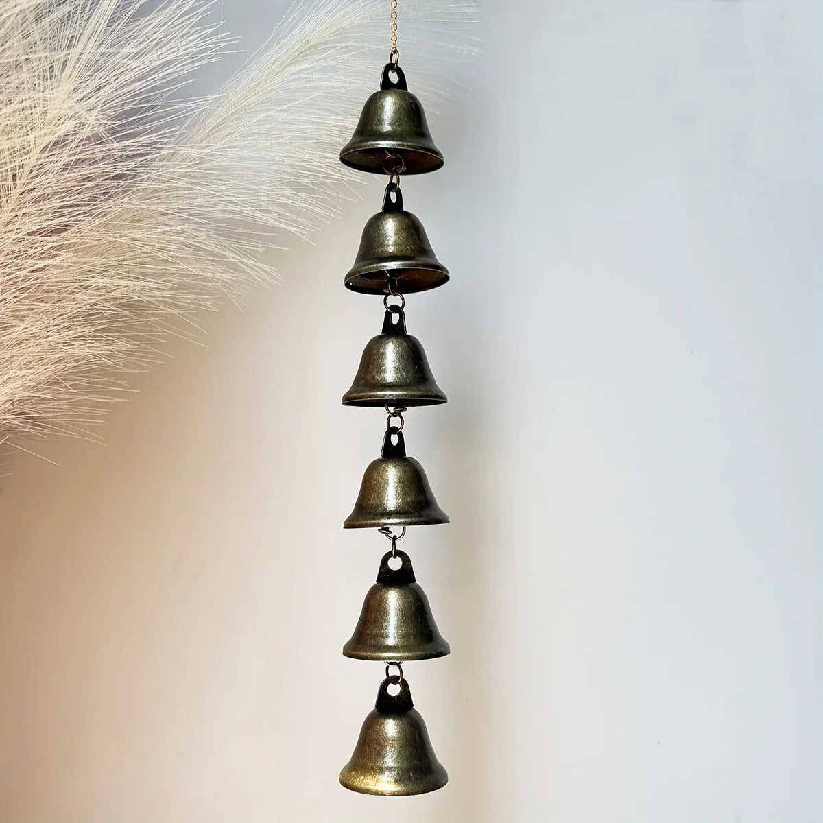 metal bell wind chime with six linked bells hanging on a chain