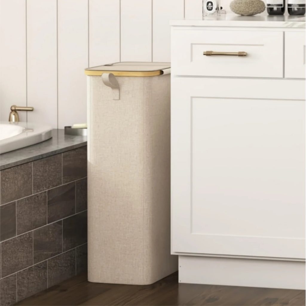 slim beige laundry basket with lid placed beside a bathroom vanity for small space use