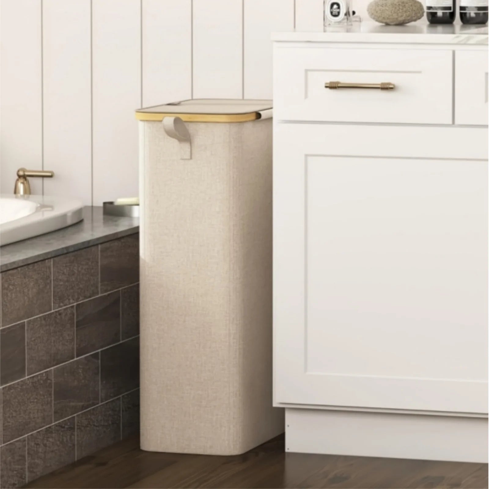 slim beige laundry basket with lid placed beside a bathroom vanity for small space use