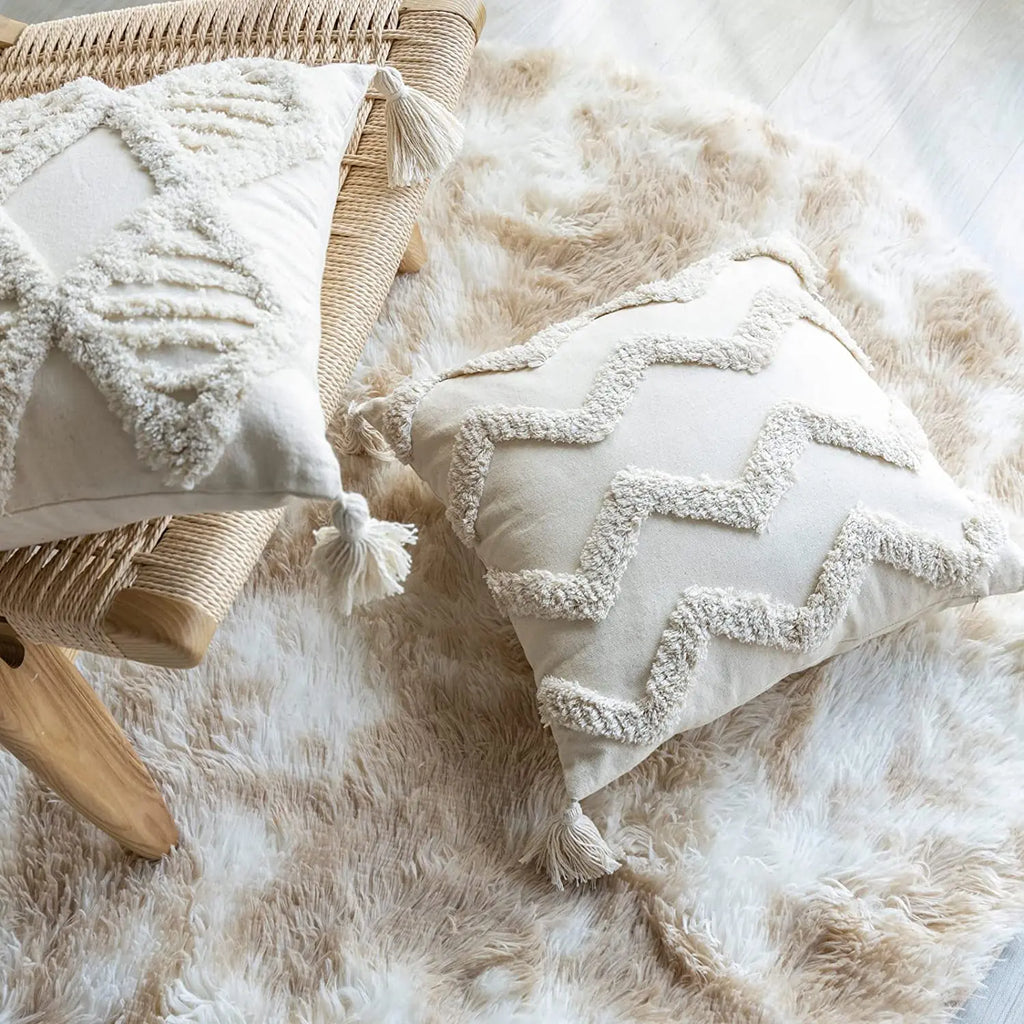 Close view of tufted cotton pillow covers with zigzag and geometric patterns on chair and floor