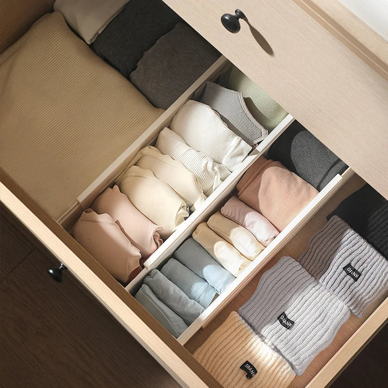 Adjustable drawer dividers used to organize folded clothes and wearables in a dresser