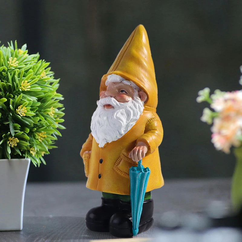 Side angle of yellow raincoat gnome statue with umbrella, displayed between plants