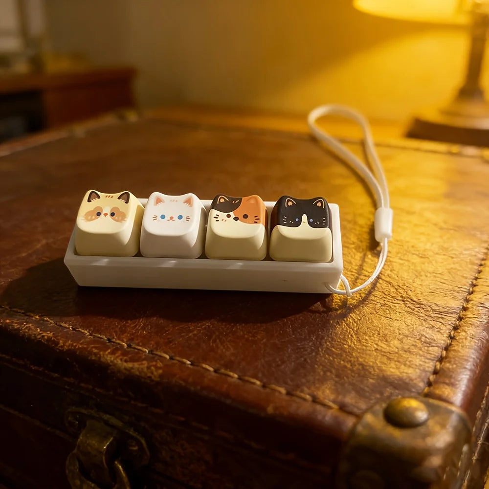 Cat key lanyard with four cat face buttons shown on a brown leather tray in warm lighting
