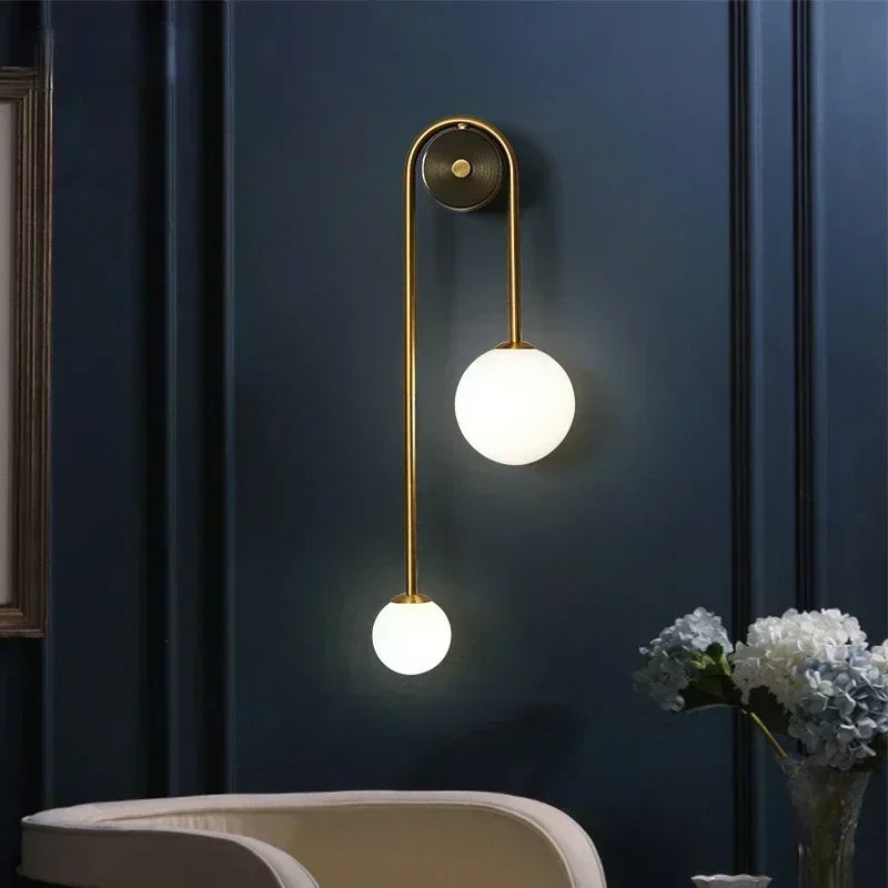 Modern double globe wall sconce with gold finish, mounted in a seating area