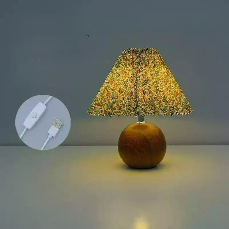 Pleated floral table lamp with USB plug and on/off switch on a white surface