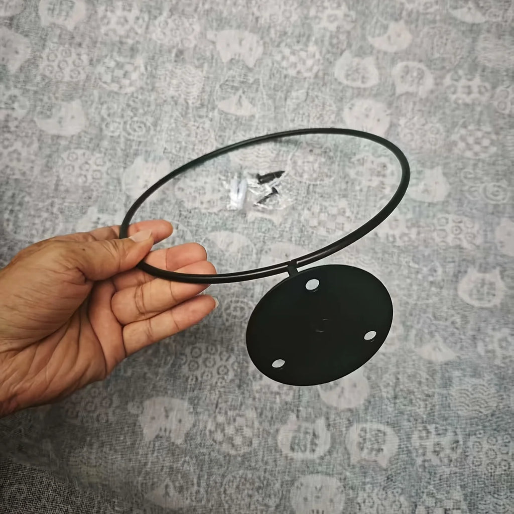 Hand holding a single black metal sports ball rack with visible mounting plate and screws