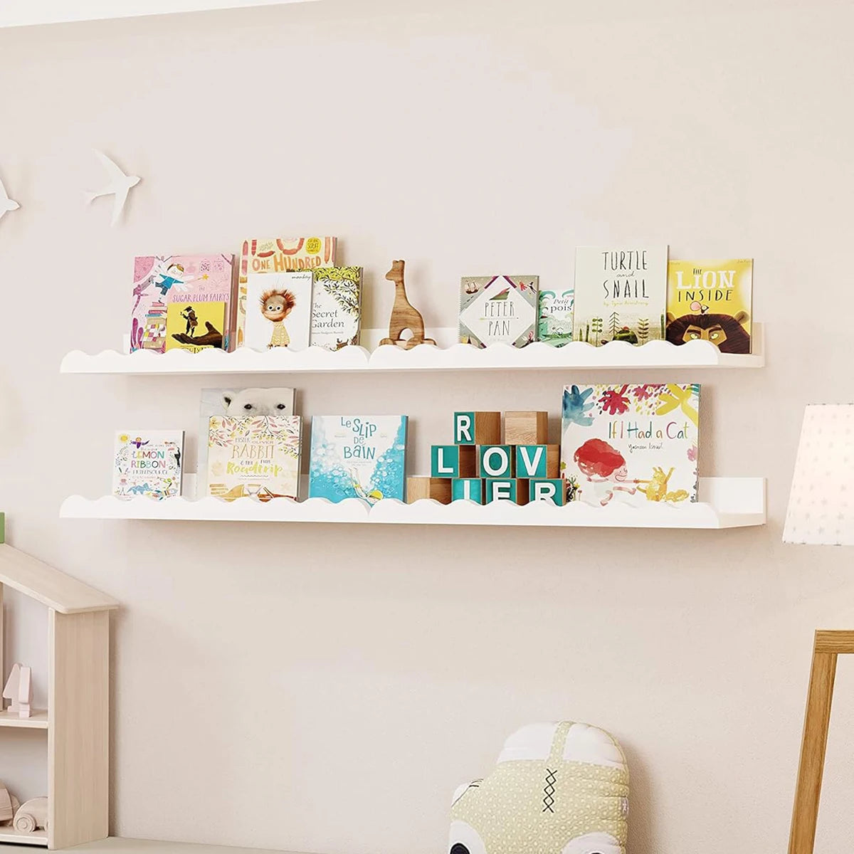 Two white wavy floating shelves in a child's room displaying picture books and toys