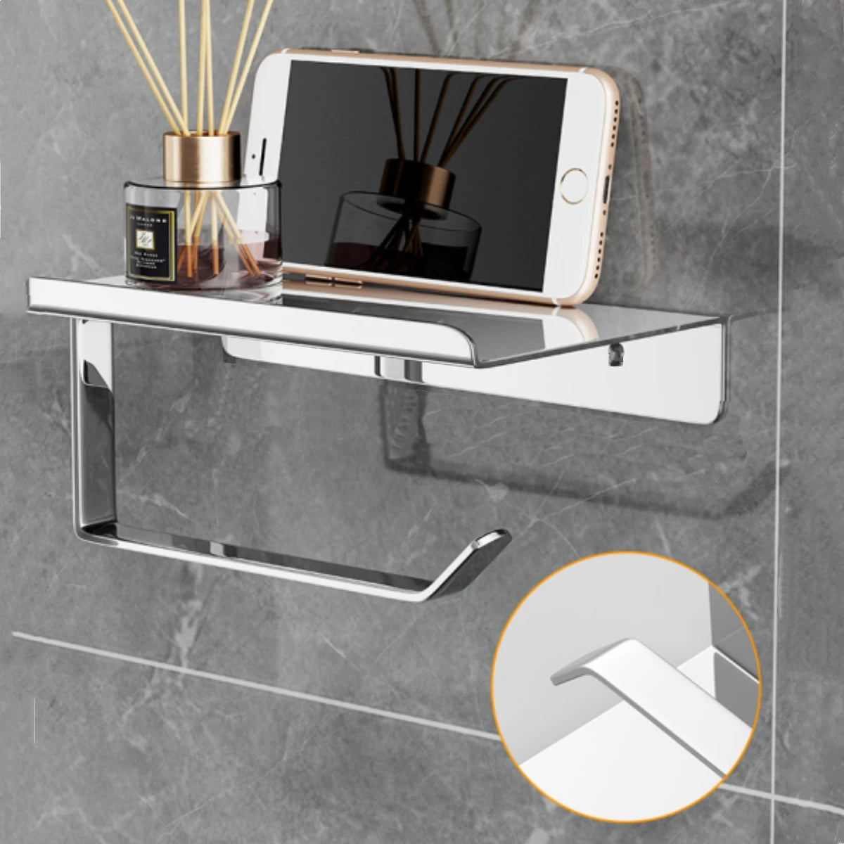 Wall-mounted silver toilet paper holder with integrated flat shelf, styled with phone and diffuser