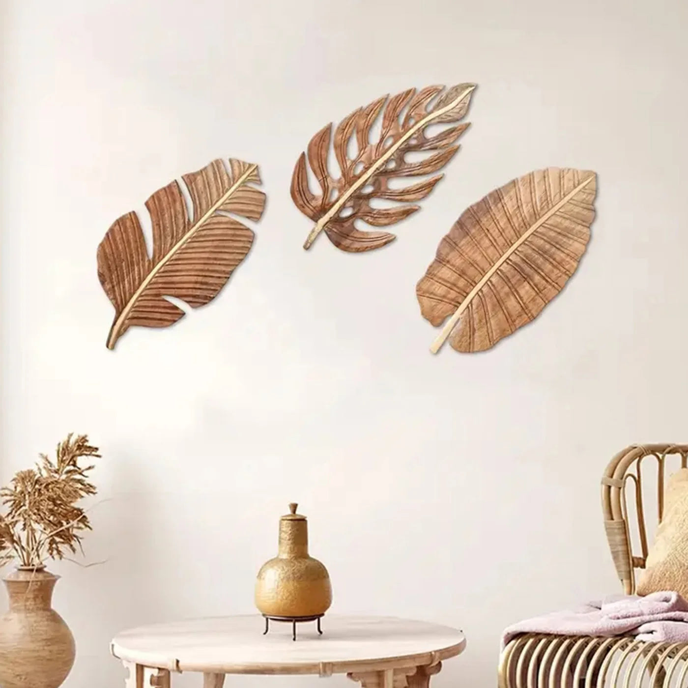 Three wooden leaf wall sculptures arranged above a cozy living room setup with natural decor