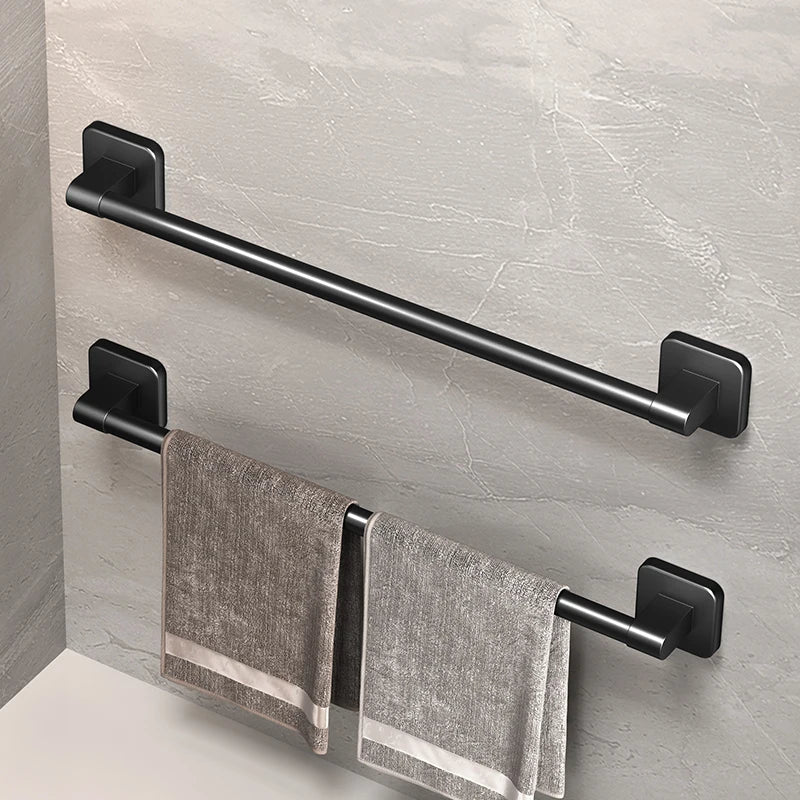 Two black self-adhesive towel bars mounted on a light bathroom wall, one holding two towels