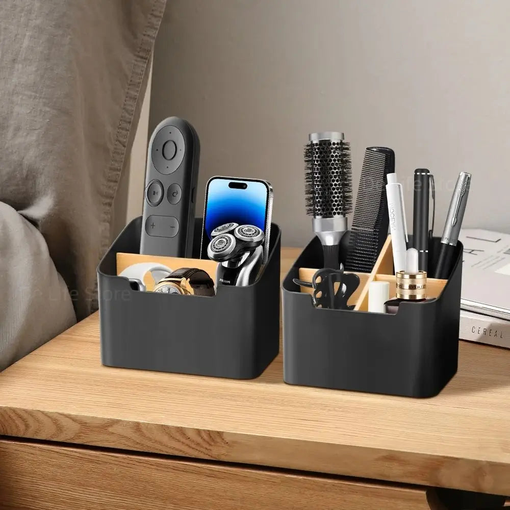 two black organizer boxes on a bedside table holding remotes, phone, brushes, and pens