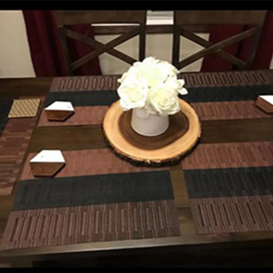 Brown and black placemat set styled on dining table with white floral centerpiece