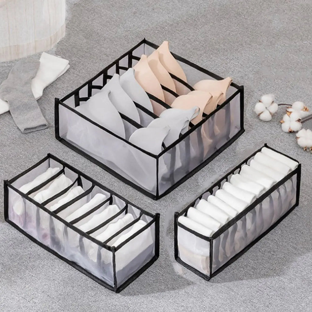 Foldable organizers in gray and white holding underwear and bras on a carpeted floor