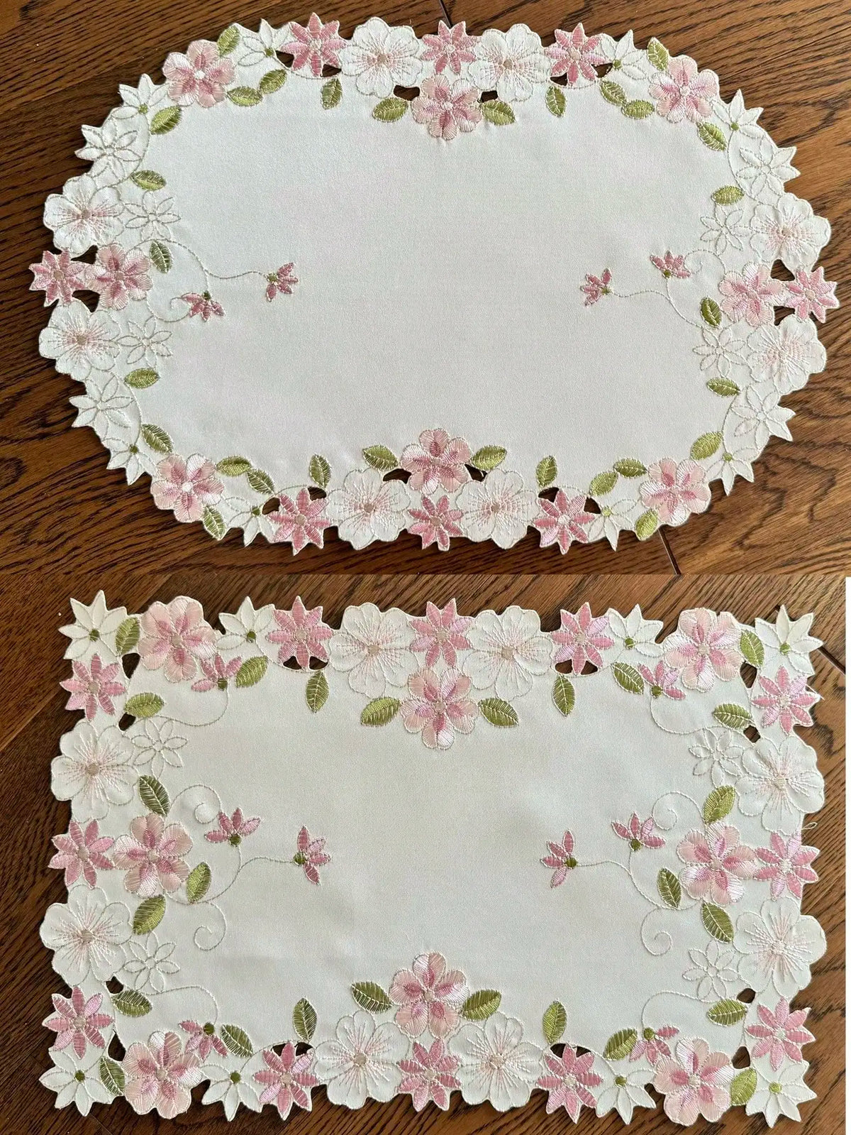 Oval and rectangular floral embroidered placemats with pink and white flowers and green leaves on a wooden table