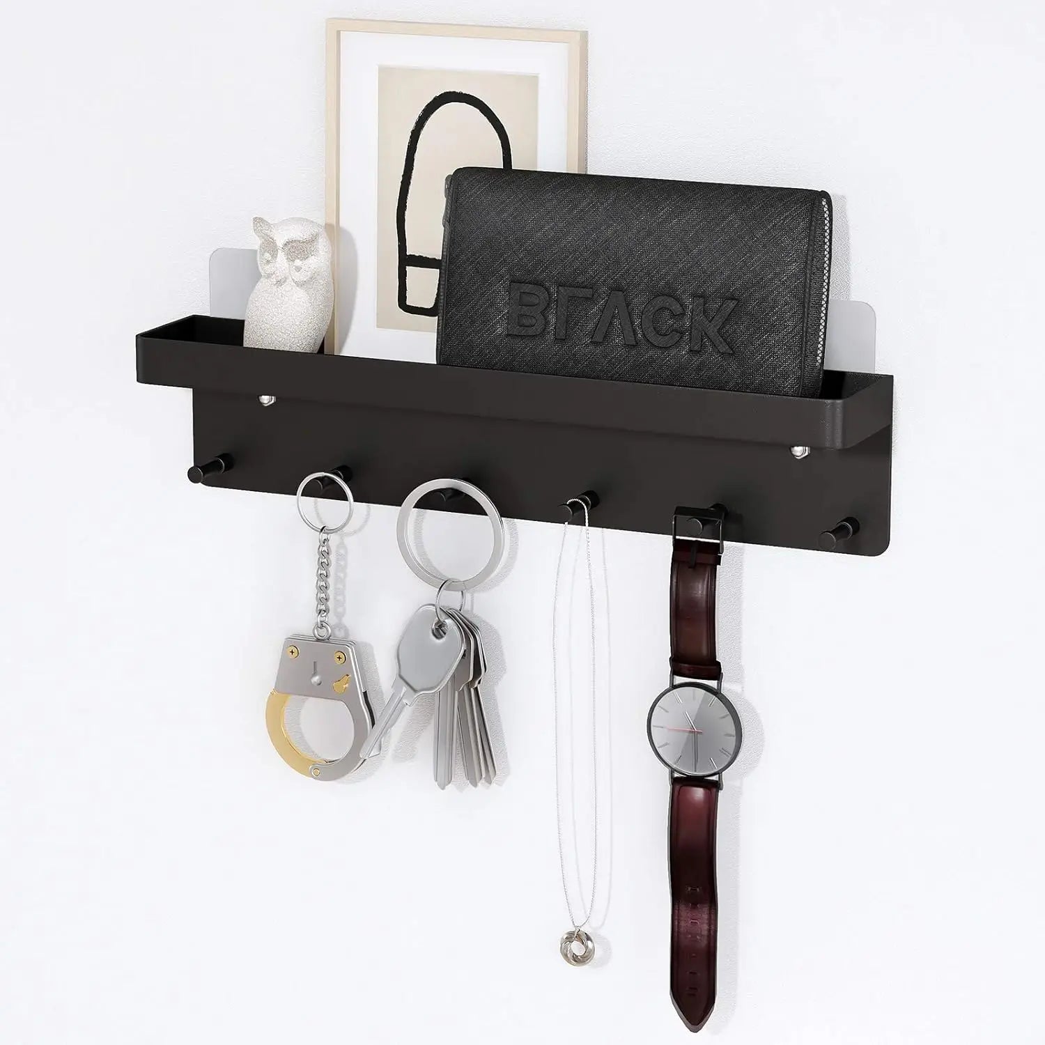 Black adhesive wall key holder with six hooks, holding keys, wallet, and small decor in an entryway