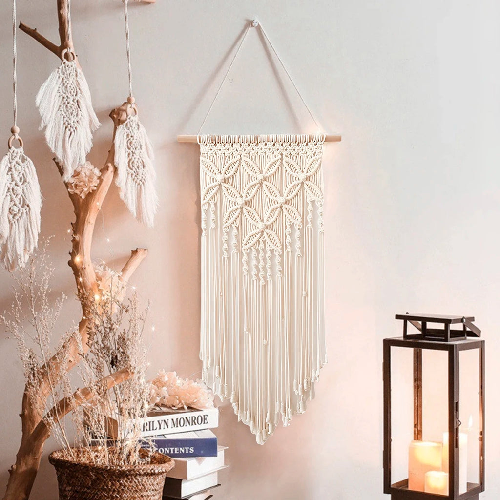 Beige macrame wall hanging styled on a wall with a lantern and decorative accents