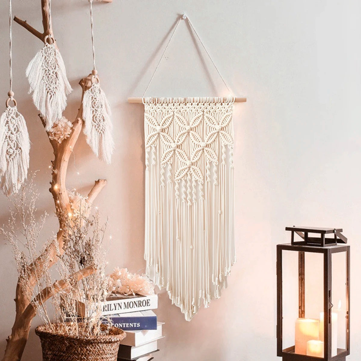 Beige macrame wall hanging styled on a wall with a lantern and decorative accents