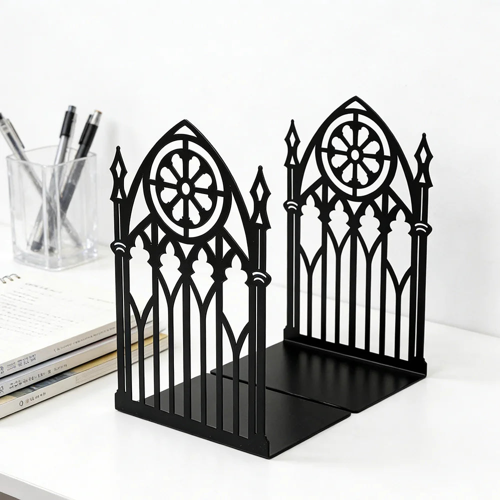 Pair of black gothic metal bookends on a white desk with books and pens