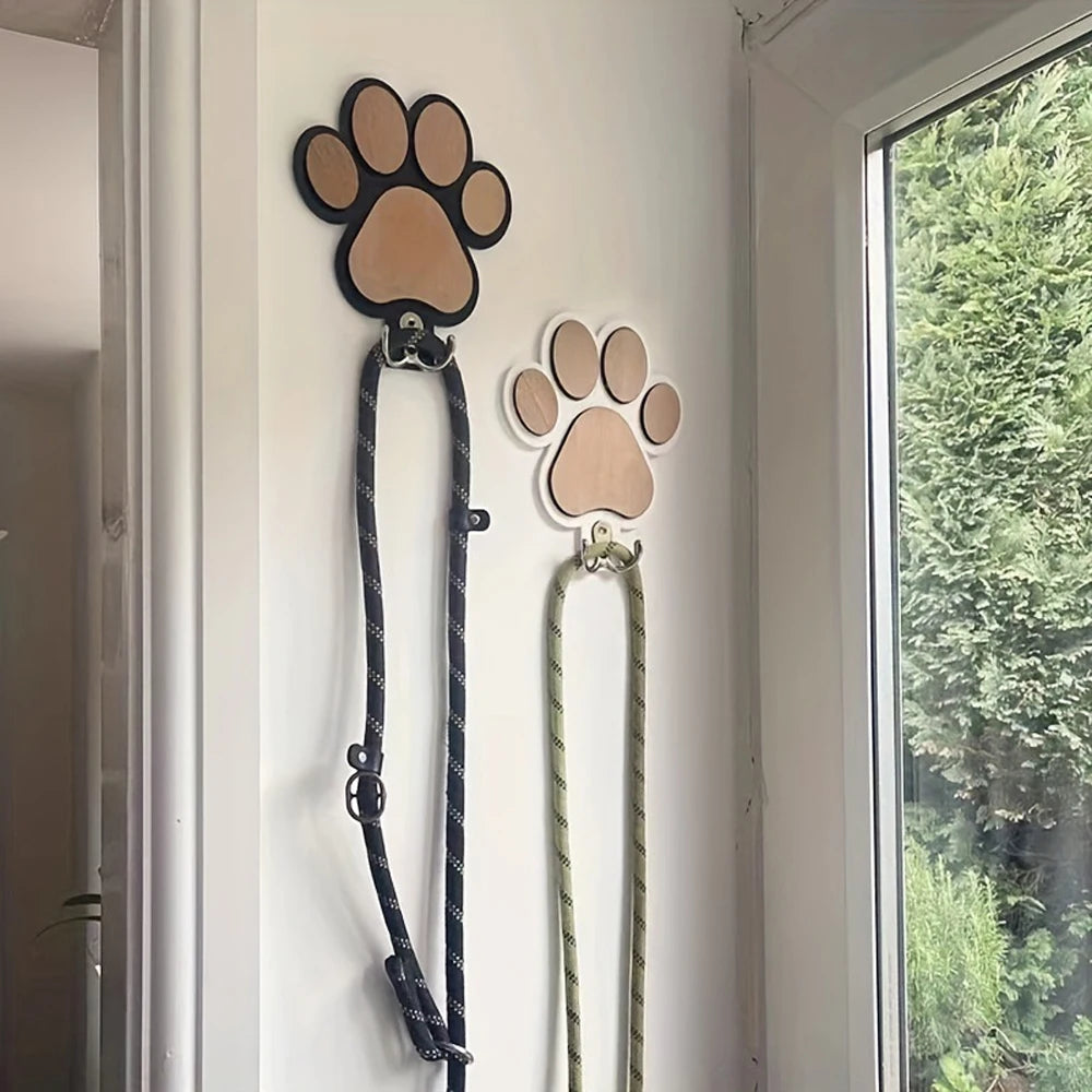Paw print wooden wall hooks in black and white used to hang dog leashes in an entryway