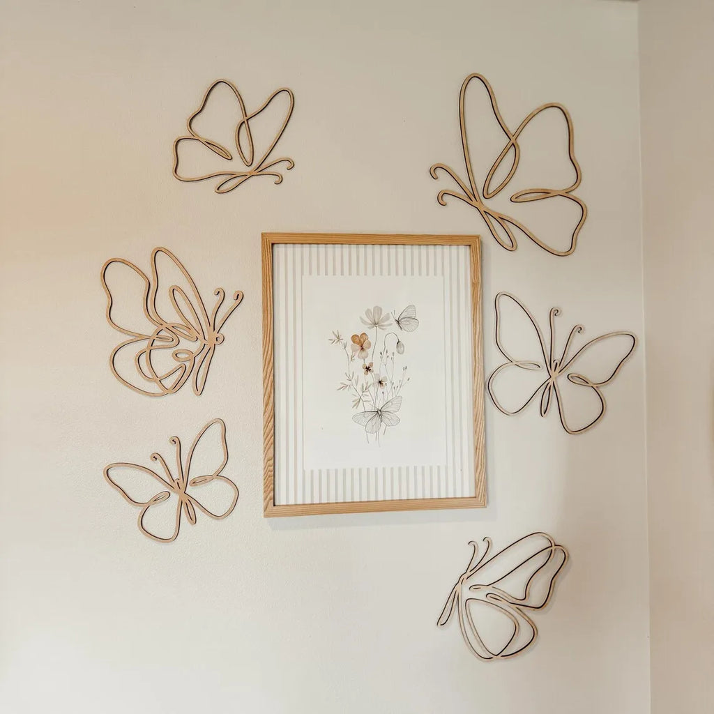 Set of six openwork wooden butterfly wall decor pieces arranged around framed art in a nursery setting