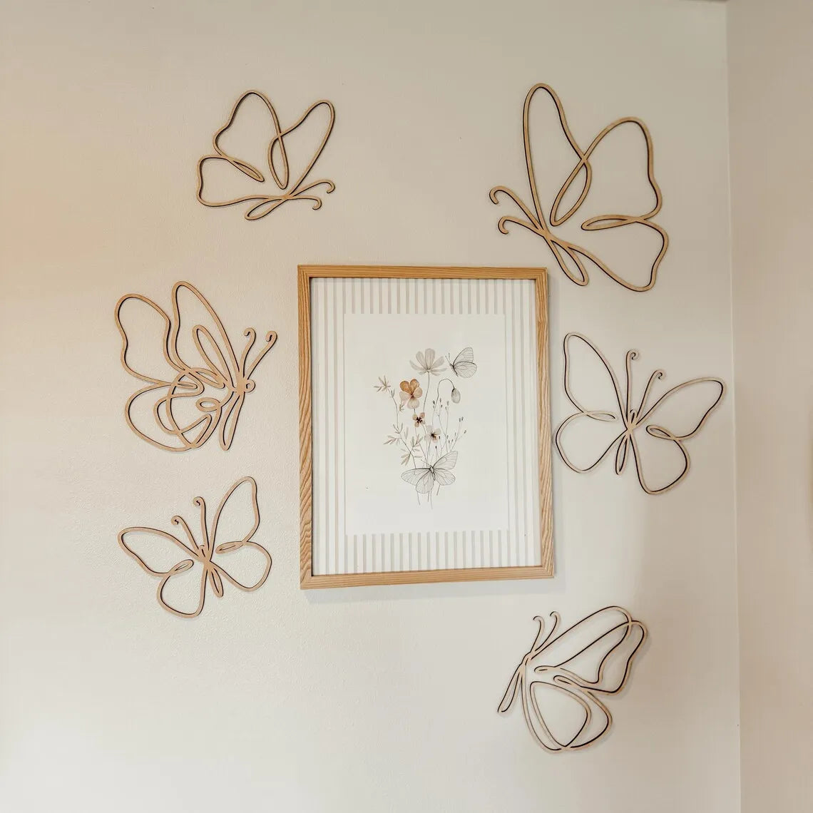 Set of six openwork wooden butterfly wall decor pieces arranged around framed art in a nursery setting