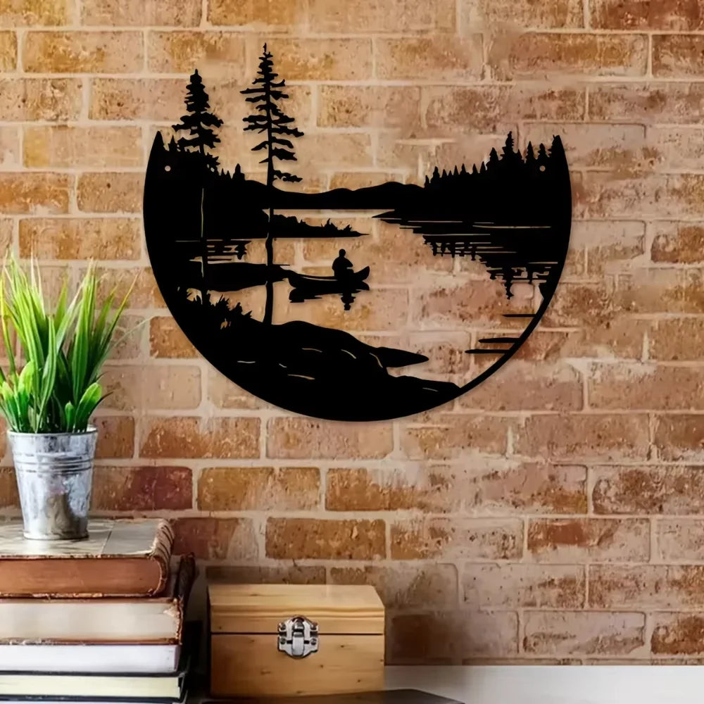 Lake and mountain round metal wall art on a brick wall above books and a plant pot
