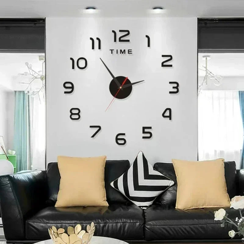 frameless wall clock with black numbers above a black sofa with pillows