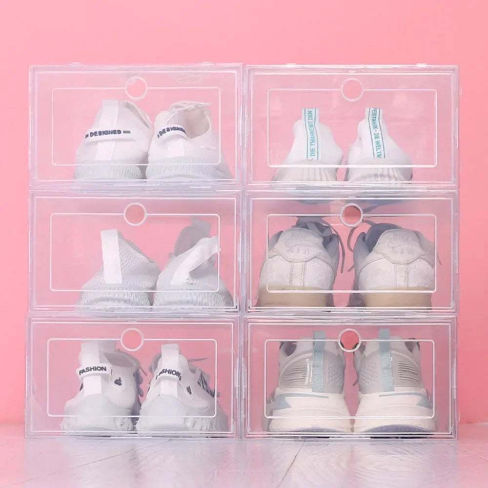 Six clear stackable shoe boxes with white sneakers, shown arranged side by side against a pink background