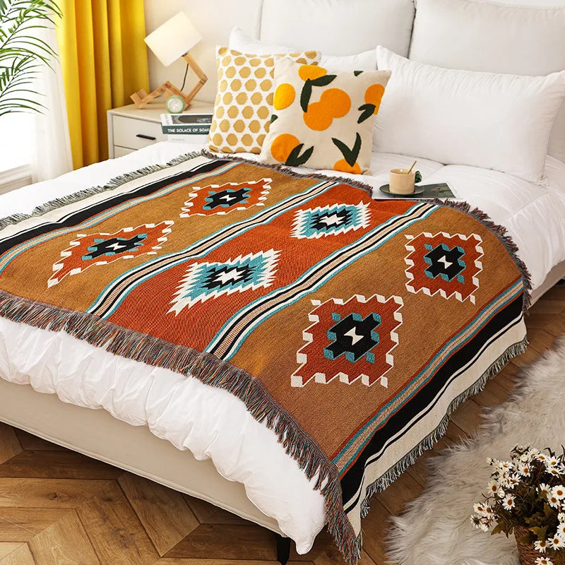 Bohemian geometric throw blanket spread on a bed with white bedding and decorative pillows