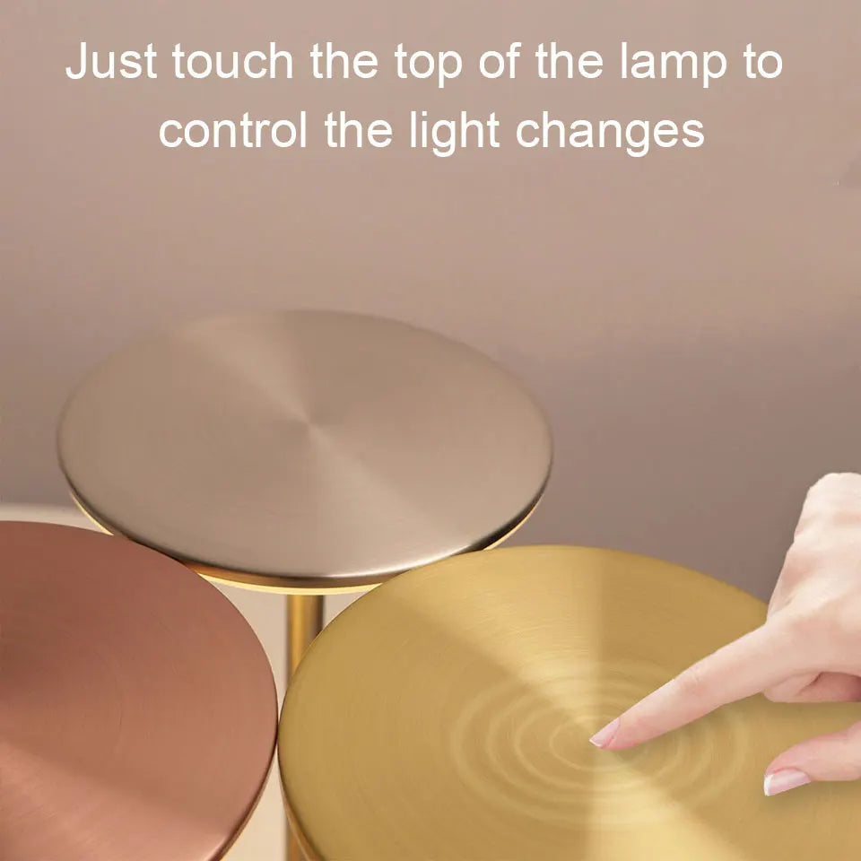 Hand touching the top of a metal LED touch table lamp to adjust settings; lamps shown in silver, gold, and rose gold