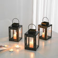 Black iron square candle lanterns with tealight candles glowing on a tabletop