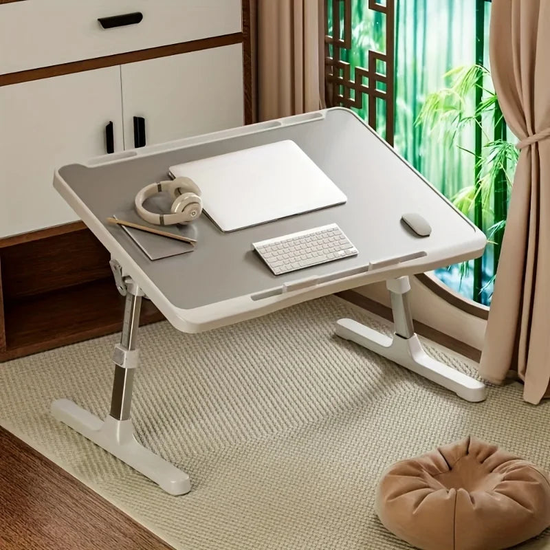 Gray lap desk placed on a bedroom floor near a window, set up for laptop work