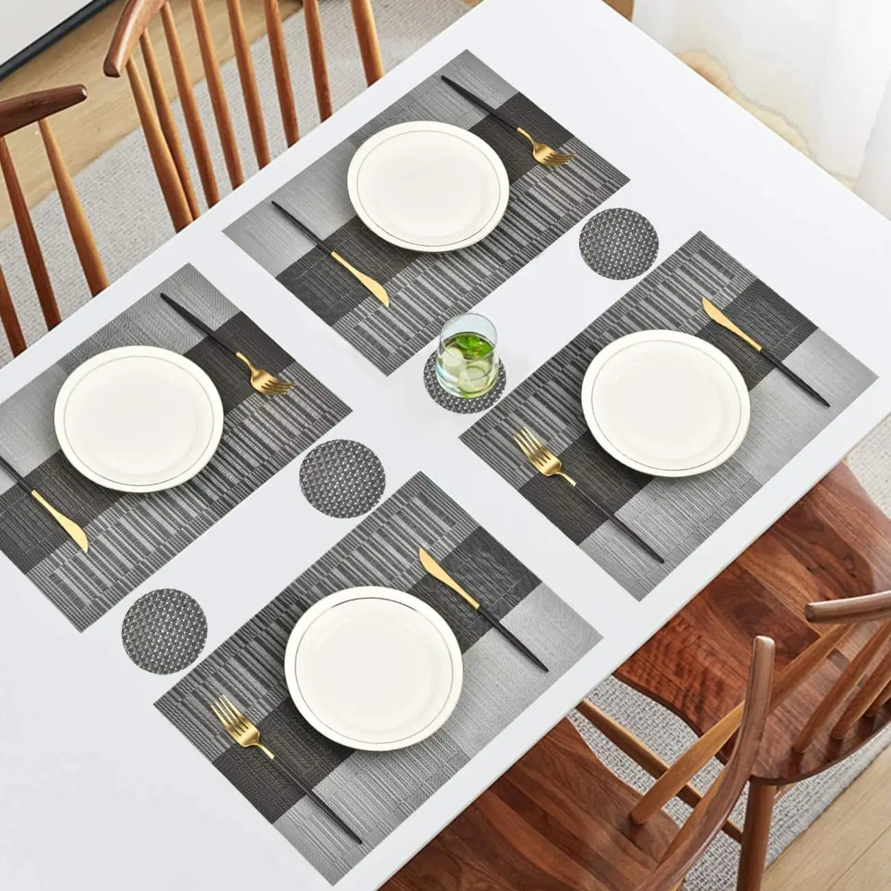 Rectangular vinyl placemats and round coasters set arranged on a white dining table with wooden chairs
