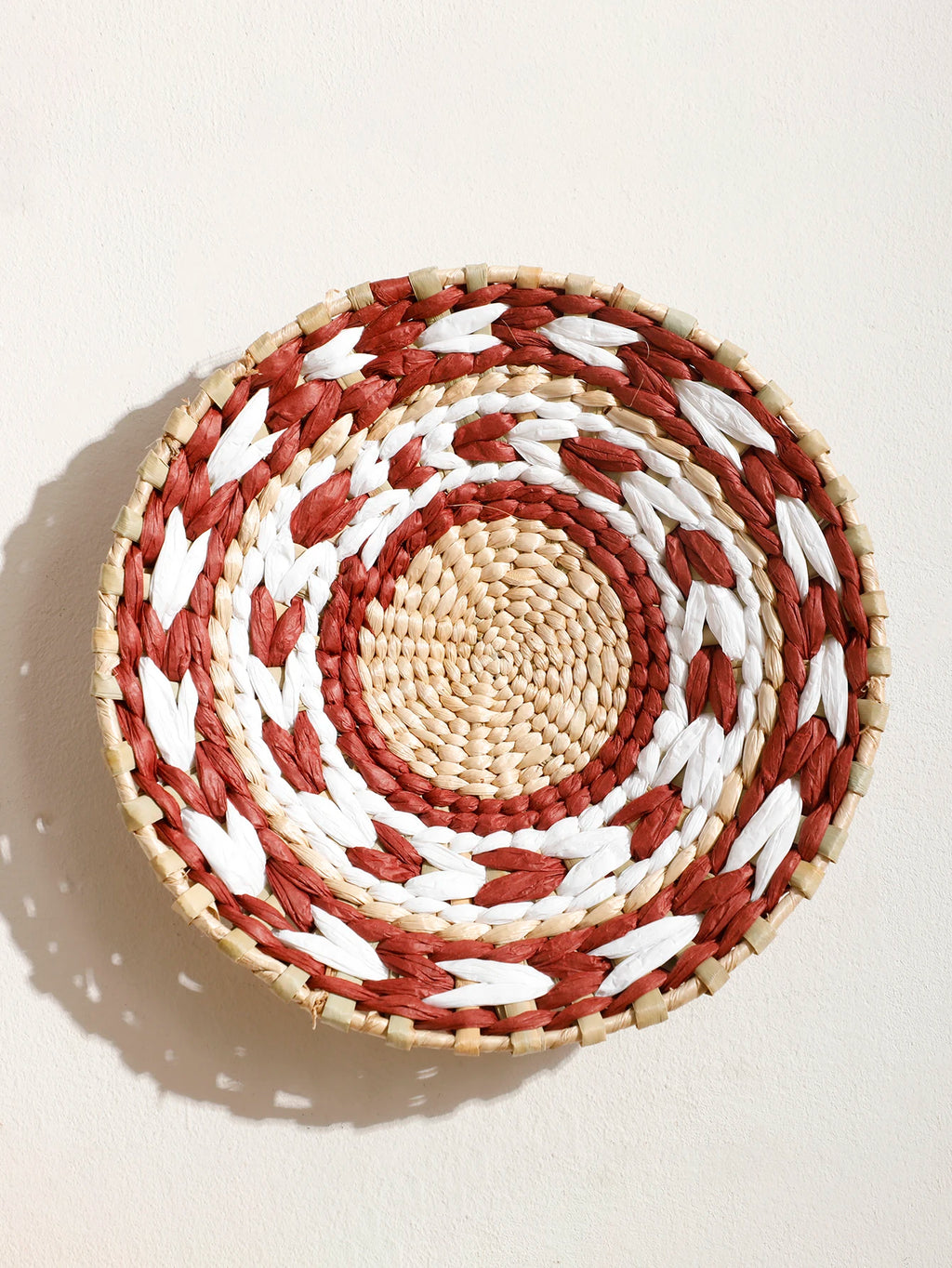 Close-up of a handwoven basket with natural, rust, and white accents for wall display