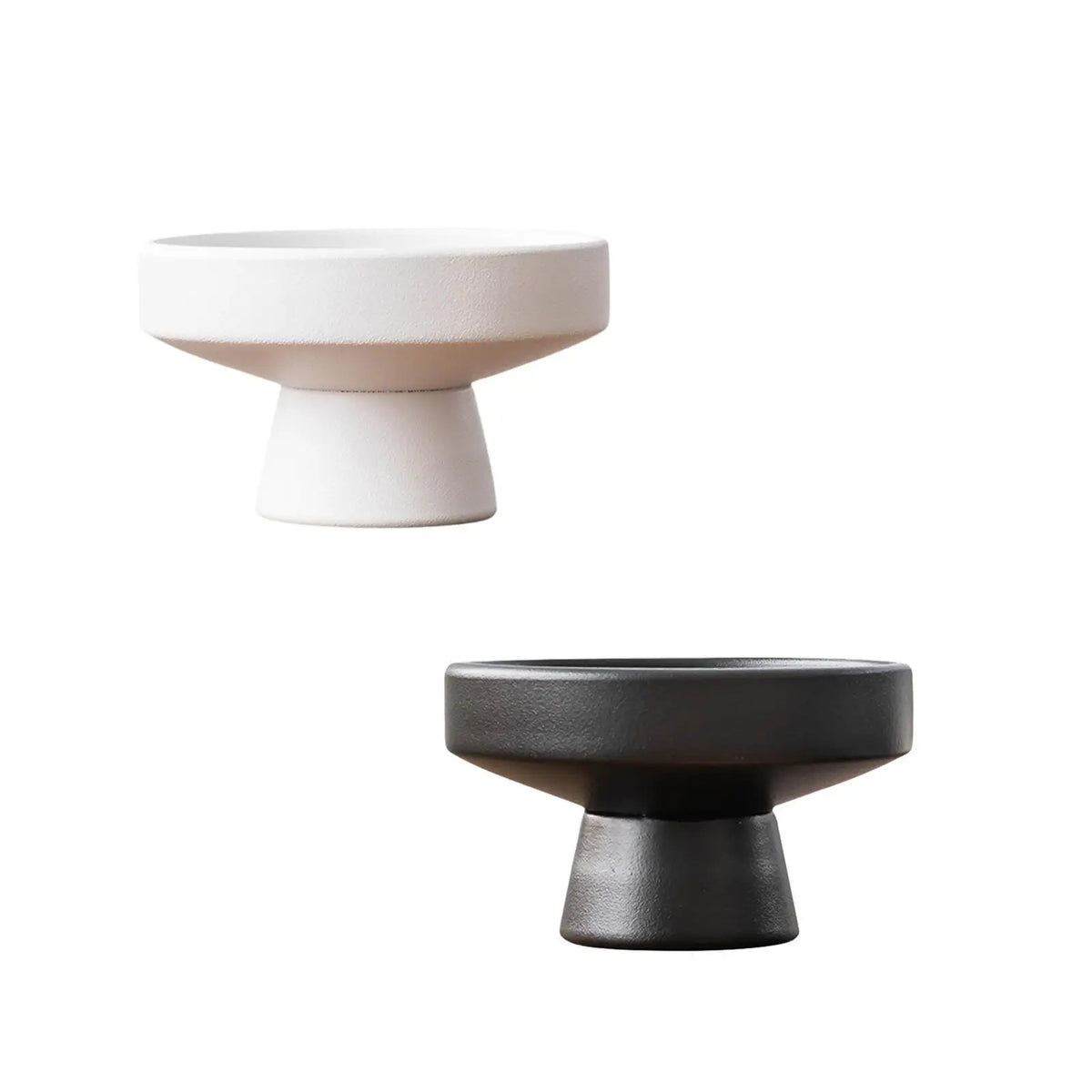 Side angle view of two modern ceramic pedestal flowerpots, white and black