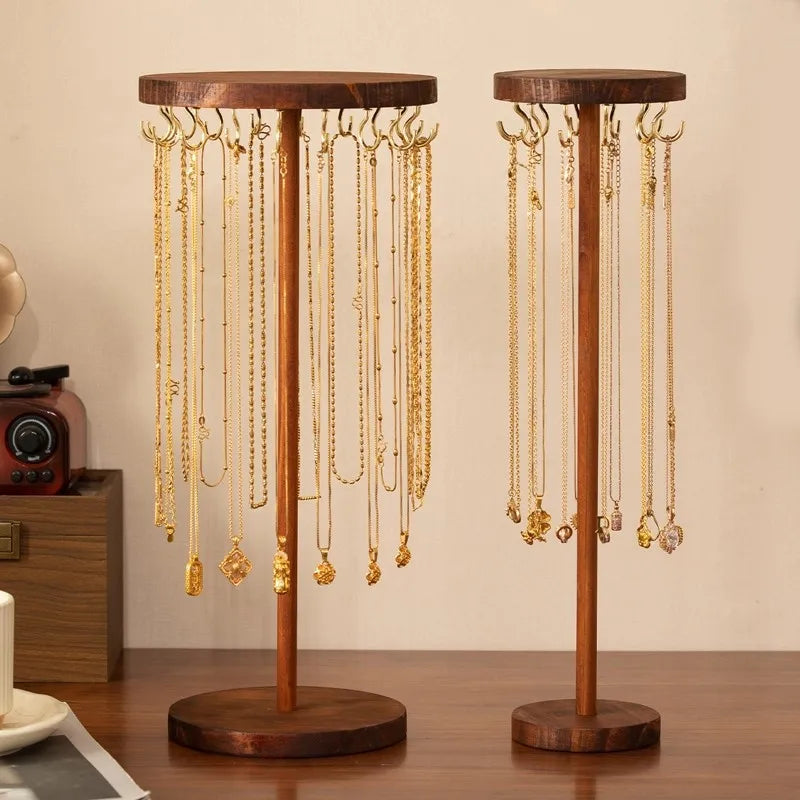 Two walnut wood necklace organizer stands with gold hooks holding multiple necklaces on a dresser