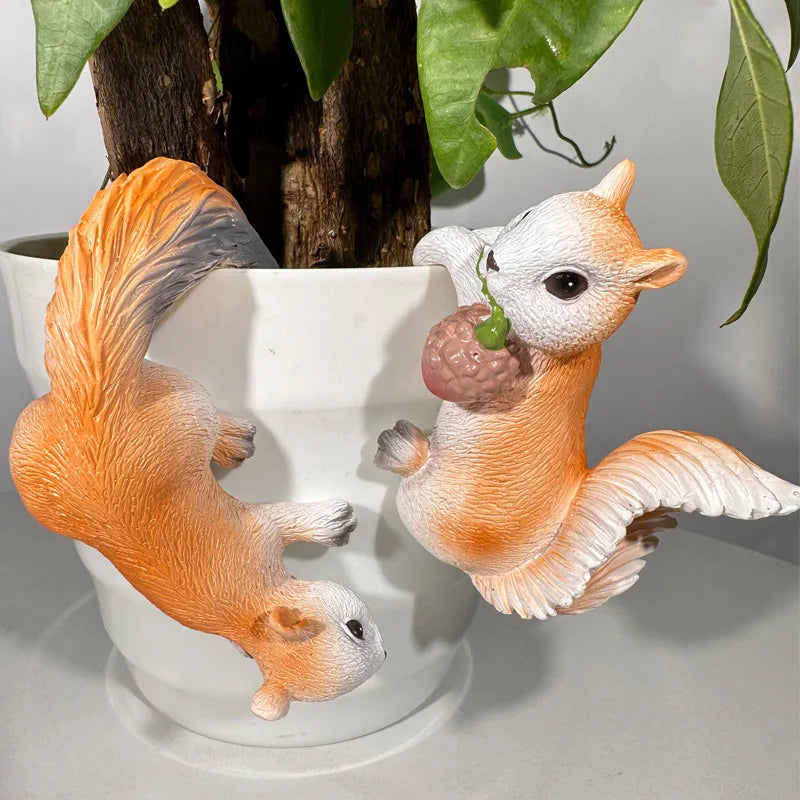 Pair of resin squirrel figurines hanging on a white plant pot