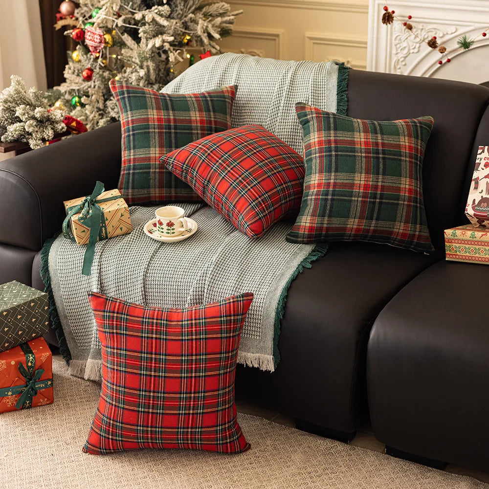 Multiple tartan plaid pillow covers on a sofa with holiday decorations in the background