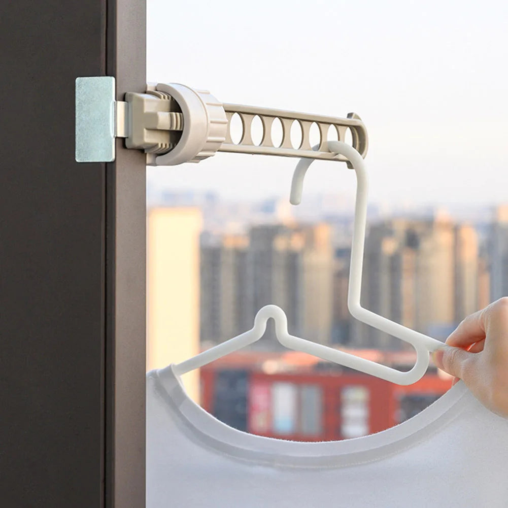 Clothes drying rack attached to a window frame, holding a hanger with a shirt in front of a city skyline.