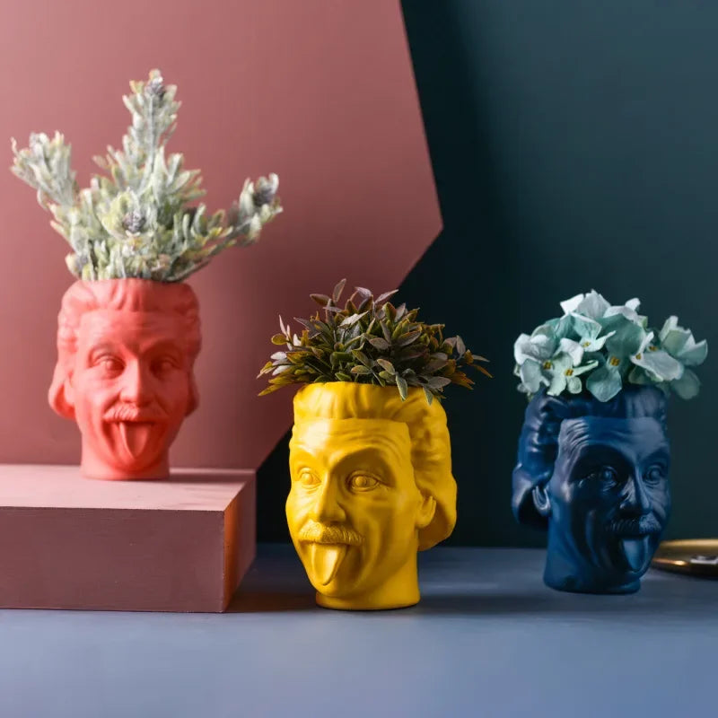 Red, yellow, and blue resin head vases displayed with greenery and flowers on a modern tabletop