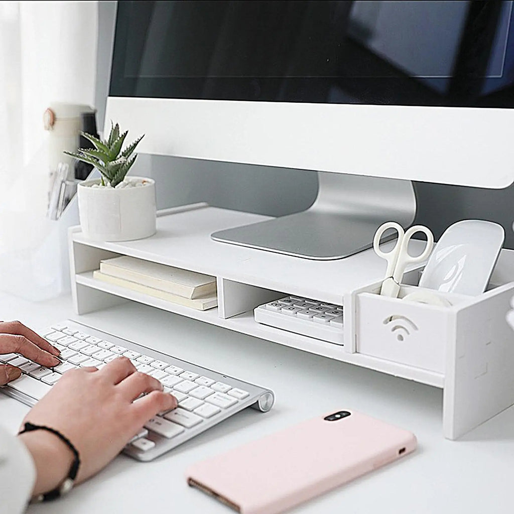 white monitor riser shelf with stationery and keyboard in a bright home workspace
