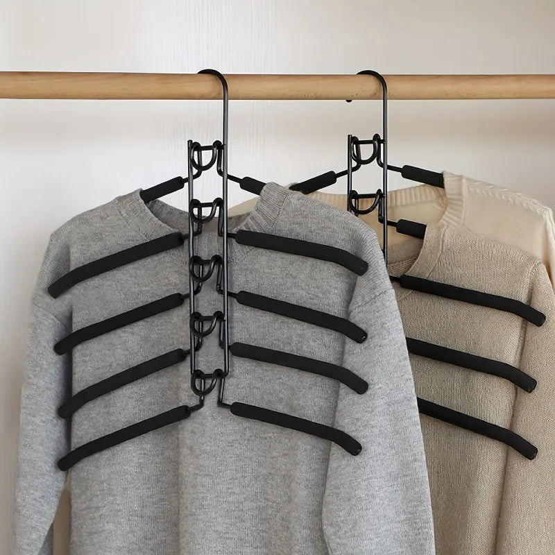Two multi-tier black hanging closet organizers holding gray and beige sweaters on a wooden closet rod