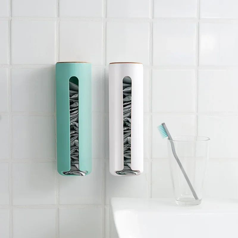 Green and white plastic bag organizers wall-mounted on white bathroom tile, glass with toothbrush nearby