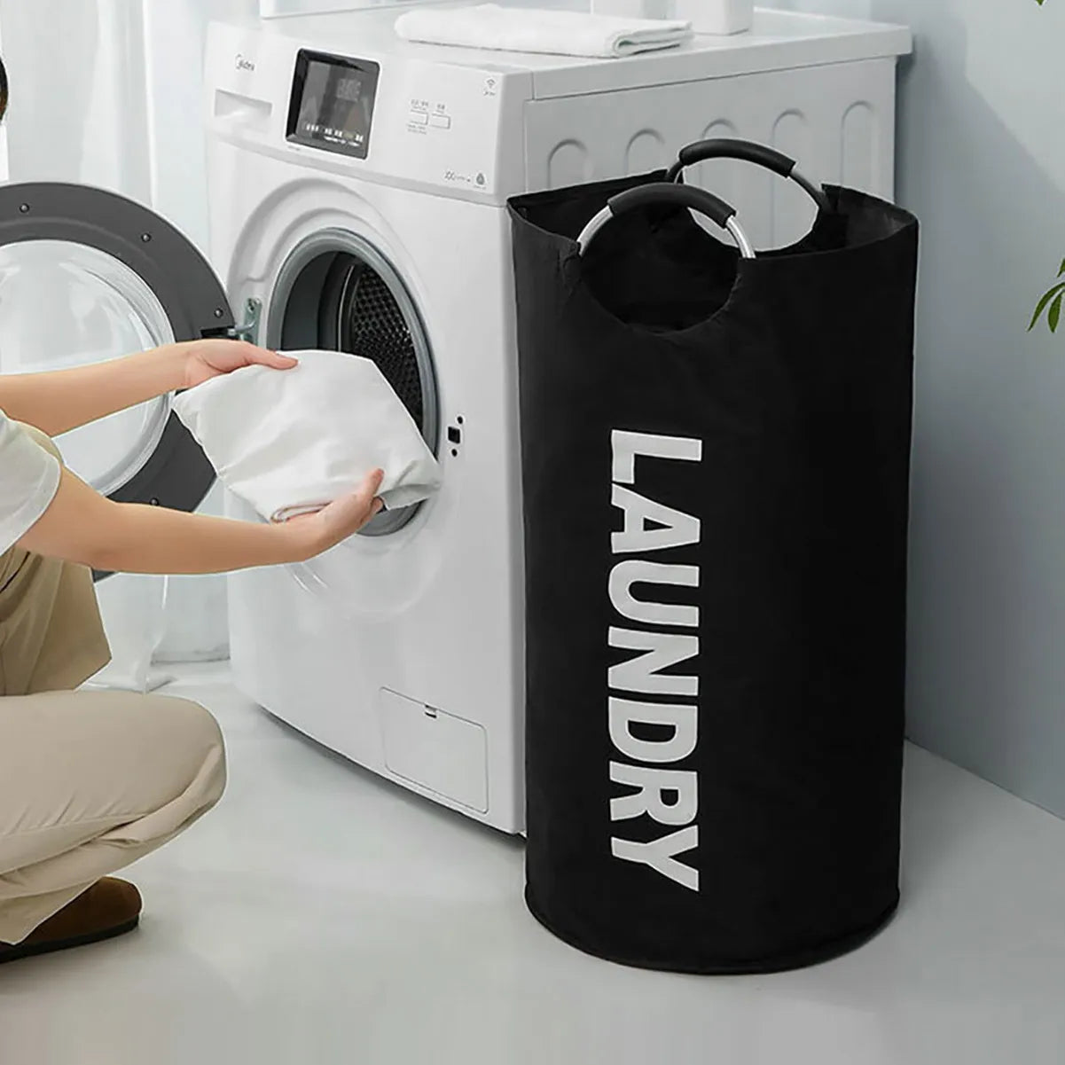 Black laundry hamper placed next to washing machine, in use scenario