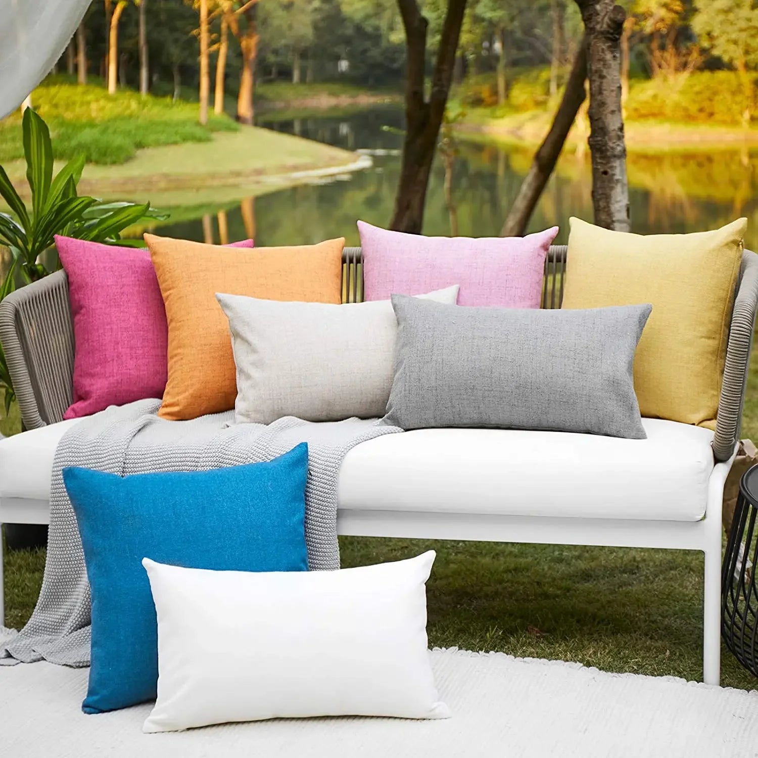 Solid color waterproof cushion covers arranged on an outdoor sofa with garden background