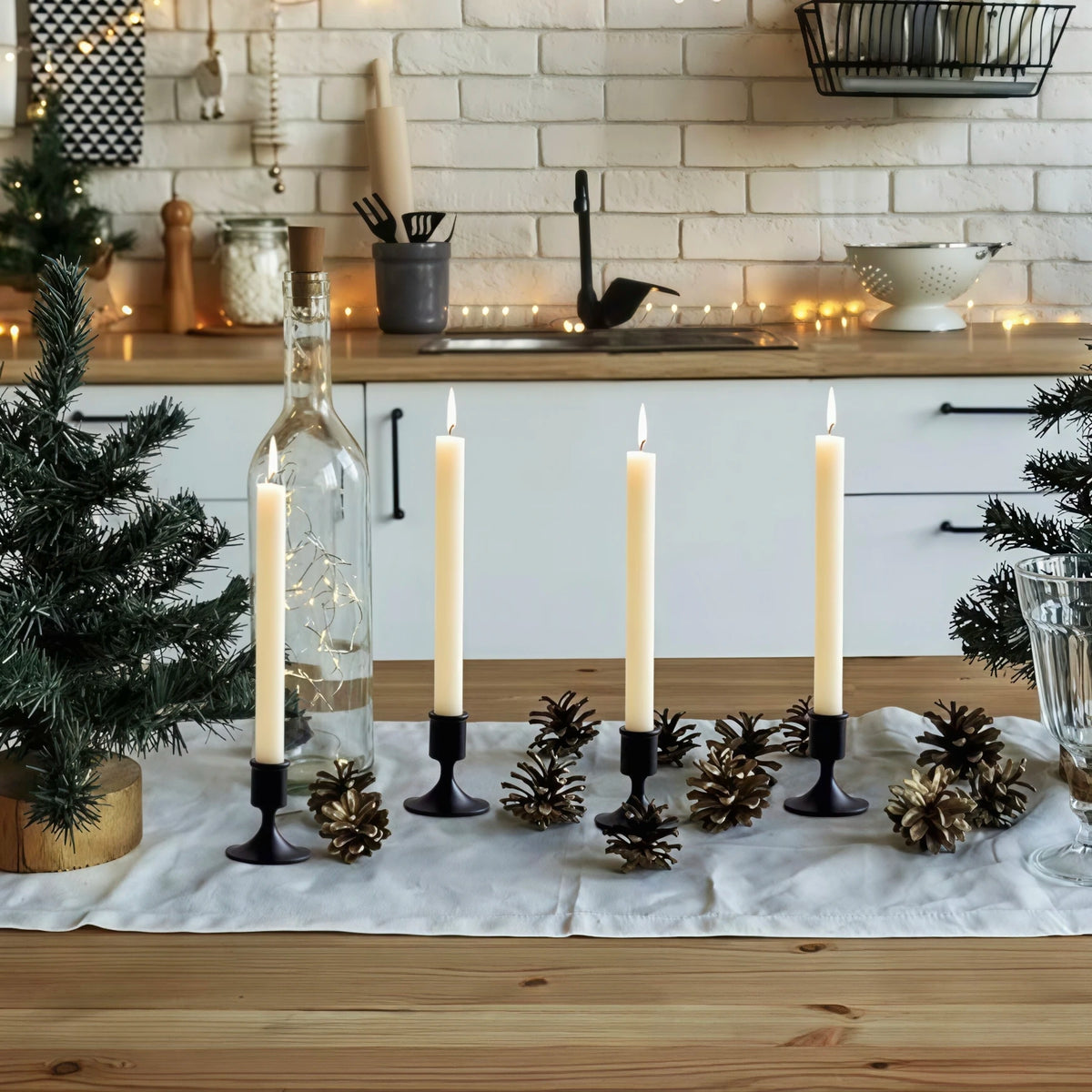 kitchen table decorated with black metal taper candle holders, pinecones, and small evergreen trees