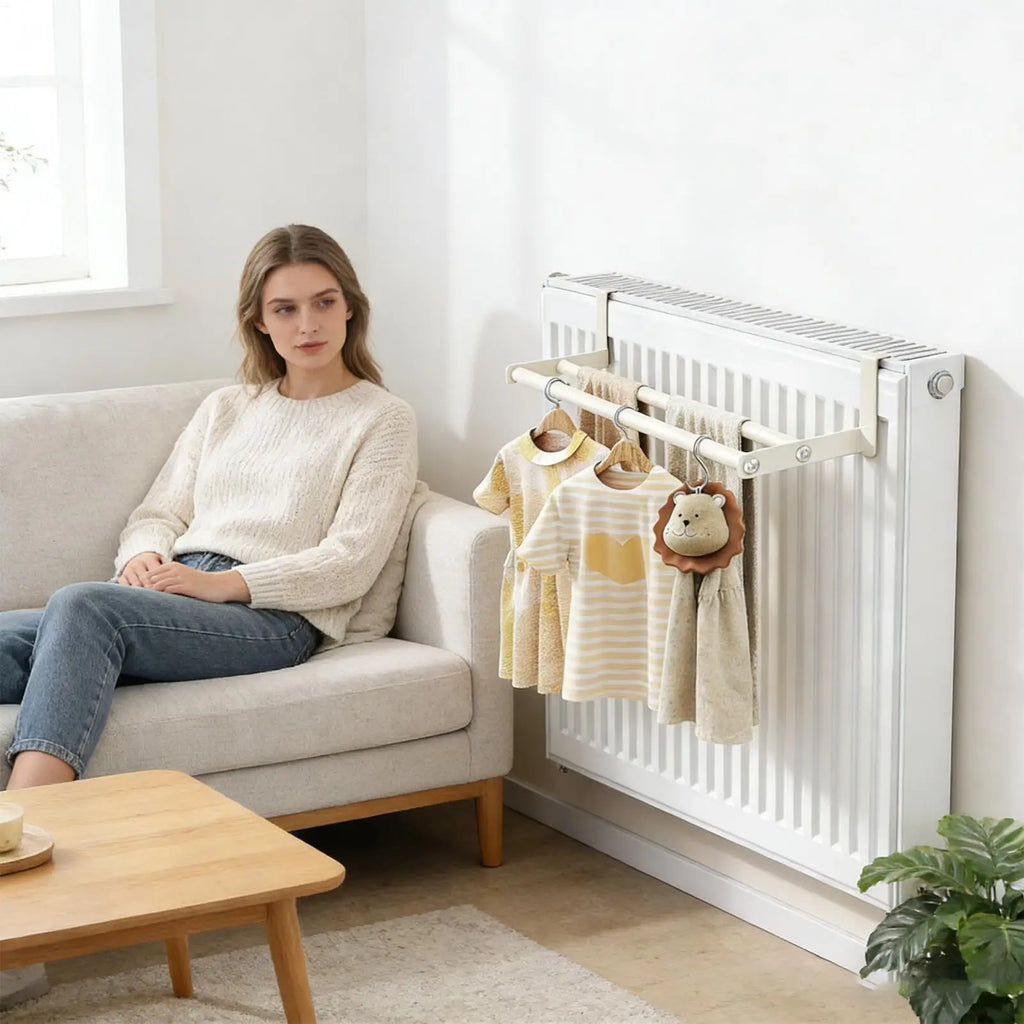Woman seated on sofa with wall-mounted radiator clothes airer in living room holding towels and children's items
