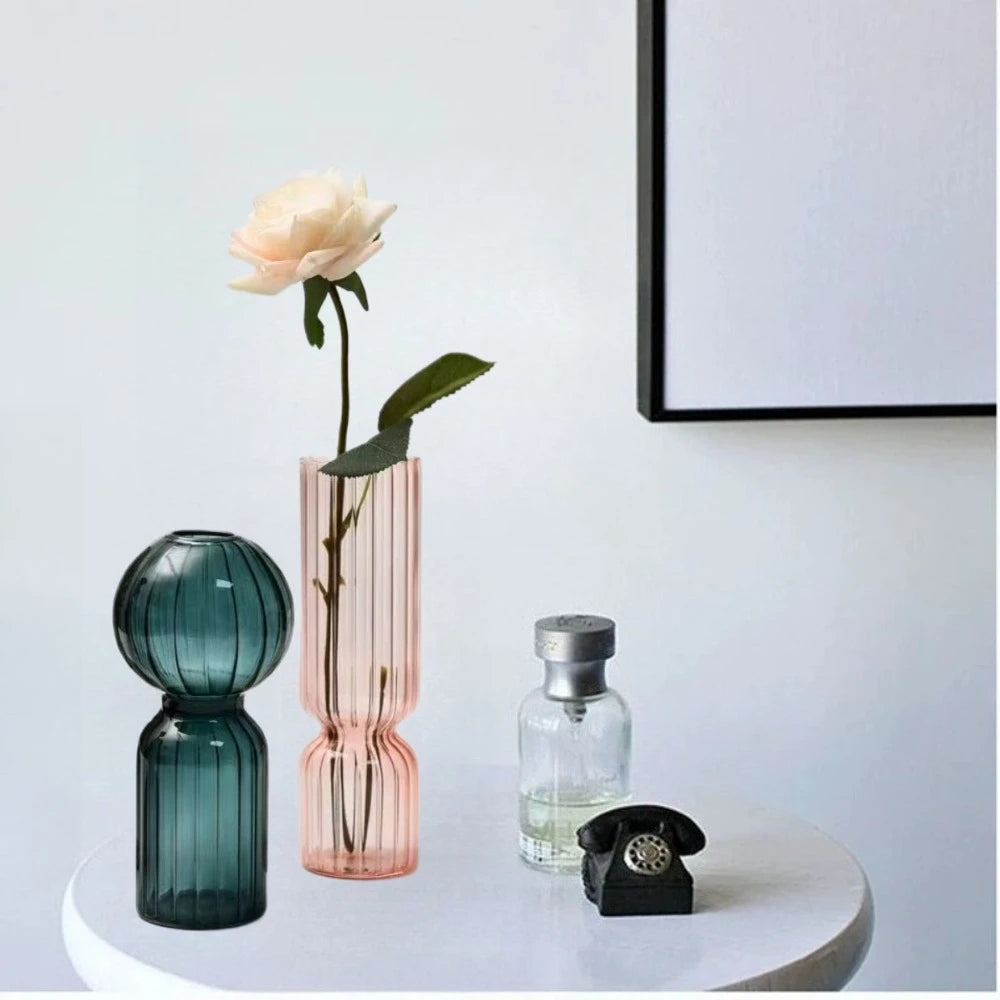 Teal and pink striped glass vases on a round tabletop, styled with a flower and decor items